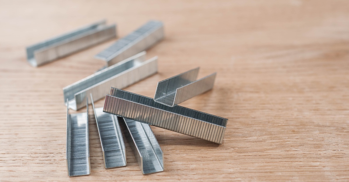 The light reflects off multiple stacks of staples stacked on top of each other, sitting on a wooden table.